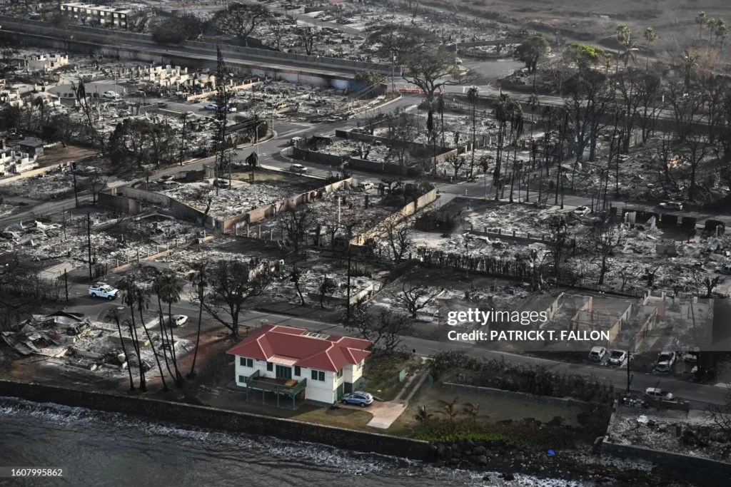 An aerial image shows a RED roofed house that survived the fires in Lahaina Maui, surrounded by buildings burned to the ground.